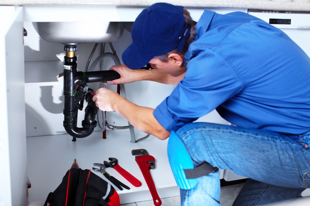 Plumber repairing pipes under sink