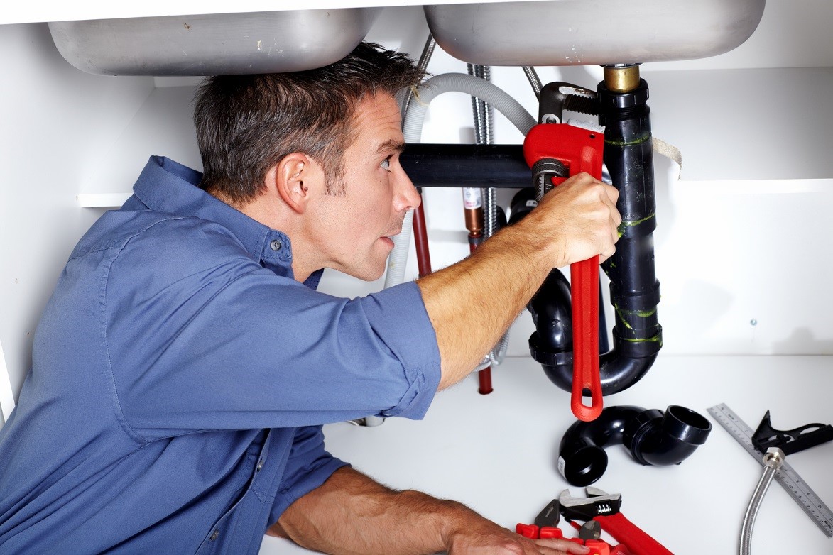 Plumber fixing pipe under sink