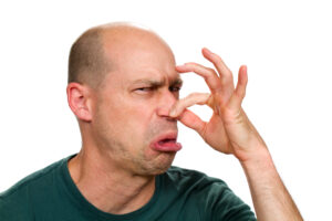 Man smells something stinky and pinches his nose to stop the bad odour.